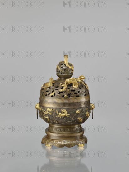Censer with a cover on a base, Qing style, Chinese art. Chinese culture. Dragons iconography, tigers, sea waves, birds, dragon with a pearl, fish, clouds, phoenixes iconography, handles, meander ornament, geometric patterns. Ceremonial/ritual vessel: censer with a high foot. Openwork cover and handles. Decoration: dragons and hôô birds on the cover; various animals on the belly. Cover with removable knob. 18th century, China. Vessel. Height 22.0 cm, width 21.0 cm, depth 17.7 cm., An ornate metal vessel with a rounded body and a domed, pierced lid sits on a matching pedestal base; the object shows a combination of dark bronze tones and bright gold accents, with gilded decorative elements including sculpted animal and dragon-like figures on the lid and body, flowing wave-like relief patterns around the midsection, ring handles with gilded mounts at the sides, a finial topped by an openwork spherical element with gold highlights, and layered circular bands and fluted motifs on the pedesta...