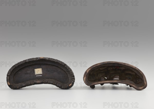 Brush stand on base., Chinese; Qing dynasty 1644–1911, 19th century. Materials and function: painting implements brush stand. Decoration: mountains, men, horses, scholars; Figure of a Hermit in a cave and other figures. Dimensions: height 21.0 cm; width 10.0 cm; depth 25.0 cm., A pair of curved, crescent-shaped objects sit side by side on a light surface against a gray gradient background; both objects are dark brown to reddish-brown with worn, textured interiors and rough, scalloped outer rims, one appearing slightly larger and flatter with a deeper, smoother inner recess and the other showing an uneven, pitted interior and small rounded protrusions along its bottom edge; overall colors visible include shades of dark brown, reddish-brown, black, and gray.