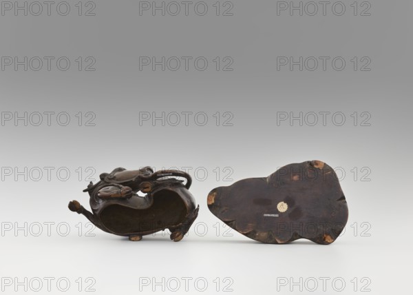 Mirror pedestal — lying unicorn on base; carved wooden base; qilin/unicorn iconography; crescent symbol; mirror; toilet accessory; Chinese art; Qing dynasty 1644–1911; 17th century; China; height 16 cm, width 11.5 cm, depth 19.5 cm., A group of two dark brown carved wooden objects resting on a pale surface against a neutral gray background, one object shown on its side revealing a hollow interior and rounded carved elements with lighter brown worn spots, the other object showing a flat underside with irregular scalloped edges and lighter brown scuffed areas, both displaying varied tones of dark brown and hints of tan.