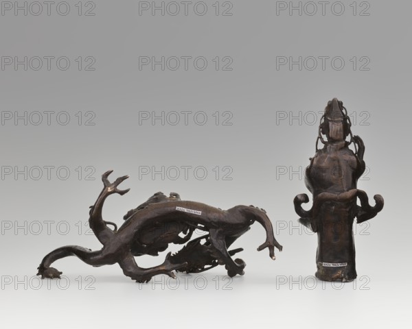 Guanyin on a dragon, Chinese, Qing dynasty 1644–1911, 18th century. Sculpture, figurine: height 15 cm, width 7.1 cm; dragon: height 4 cm, width 8.3 cm. Subject/iconography: Guanyin bodhisattva of mercy riding a dragon, dragon with a pearl; materials and style: Chinese art, Buddhism, dragons, goddesses., A group of dark brown sculptural objects sits on a smooth light gray surface against a soft gray background; one object lies horizontally with sinuous, branching limbs and claw-like ends, showing a few lighter brown highlights at the tips, while a taller, upright object beside it has a bulbous top, curving protrusions on its sides, and a slightly glossy dark brown finish with subtle lighter brown areas.