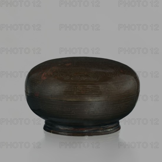 Box with lid; Chinese, Qing dynasty 18th century; carved vessel for writing implements decorated with dragons dragon with a pearl inlaid with silver thread; height 4.5 cm, diameter 7.2 cm., A rounded, lidded container with a short pedestal base, shown against a light gray background; the object has a smooth, domed top and a bulbous body with faint decorative incised patterns, and its surface shows worn areas and subtle reddish highlights; visible colors include dark brown, black, muted red, and hints of gray on the base and background.