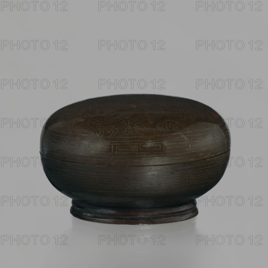 Box with a lid; Chinese; Qing dynasty 1644–1911, 18th century; decorated with dragons dragon with a pearl motif inlaid with silver thread; used for writing implements; vessel; height 4.5 cm, diameter 7.2 cm., A rounded, low-profile wooden container with a lid sits on a small circular base; the object shows a smooth, dark brown surface with subtle carved or incised decorative patterns barely visible across the top and sides. The container displays a few areas of lighter brown and reddish-brown tones where the finish varies, and the background is a pale gray. The overall colors visible are dark brown, lighter brown, reddish-brown, and gray.