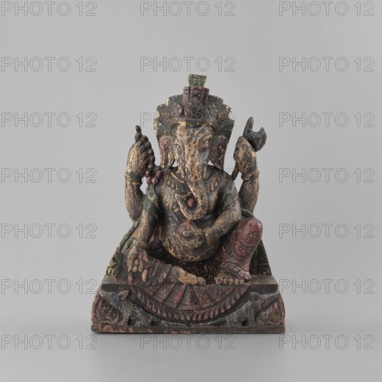 Ganesha, unknown artist, late 18th century, Nepal; sculpture height 26.0 cm, width 19.5 cm, depth 8.2 cm; iconography: lotus, elephants, axe, mounts, flowers, rats; attributes: bracelets, necklaces; religion/culture: Hinduism, Shaivism, Indian art., A carved figurine of an elephant-headed figure seated on a decorated base, with a rounded belly and multiple arms arranged around the torso, showing worn painted surfaces in colors including brown, black, red, green, and traces of gold; the figure wears a tall ornate headdress and has detailed facial features and large ears, and one leg is bent while the other rests on the base, which is carved with geometric and curved patterns and shows chipped and aged texture.