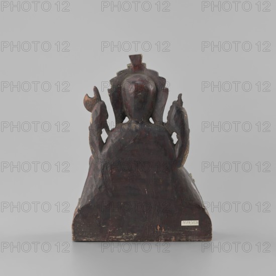 Ganesha, lotus iconography, Indian culture, elephants, axe iconography, religion, mounts, flowers, rats, Shaivism, bracelets, Hinduism, necklaces, late 18th century, Nepal, sculpture, height 26.0 cm, width 19.5 cm, depth 8.2 cm, A worn wooden sculpture seen from the back, with a rounded central head and a decorative backplate, flanked by sculpted side elements that curve upward; the surface shows chipped and uneven areas and layers of paint; visible colors include dark reddish-brown, black, hints of gold, and small areas of lighter exposed wood; the sculpture sits on a flat rectangular base against a plain light gray background.