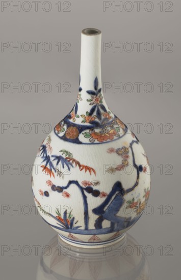 Bottle, ca. 1700–1730, porcelain; Arita, Japan. Height 22.3 cm, diameter 12.2 cm. Decorated in Imari palette with motifs of bamboos, pines, and plums — the Three Friends of Winter — associated with sake vessels; Japanese ceramicist/author unknown., A ceramic vase with a long narrow neck and a bulbous body, shown against a plain gray background. The vase is primarily white with visible crackle glazing and is decorated with painted floral and botanical motifs in dark blue, orange, green, red, and gold. The neck features dark blue leaf-like shapes and small orange and green flowers, while the rounded body displays dark blue branches and stylized foliage, orange and red flowers, green leaves, and gold-accented blossoms. A dark blue band encircles the lower body above a narrow foot ring, and the base reflects softly on the surface below, showing muted gray and the vase’s painted patterns.
