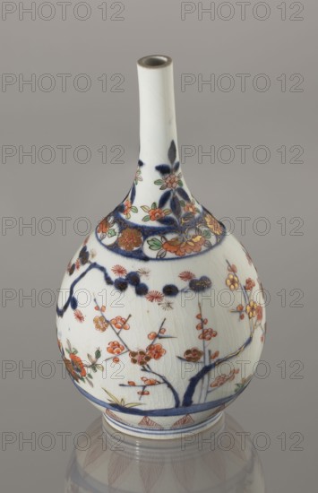 Bottle, porcelain, Arita, Japan, ca. 1700–1730; height 22.3 cm, diameter 12.2 cm. Decorated with bamboos, pines, plums the three friends of winter, sake motif, imari palette; Japanese ceramicist/, A slender-necked porcelain vase with a bulbous body sits against a neutral gray background, its surface predominantly white with visible crackle glaze; the decoration includes a group of orange and red floral motifs with green leaves, dark blue branches and accents, and areas of gold detailing, plus a band of dark blue near the base and rim, and a reflection of the vase visible on the smooth surface below.