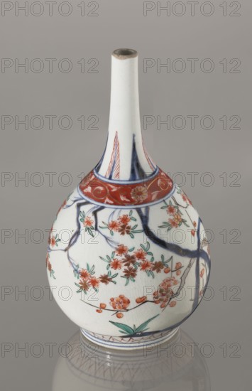 Bottle, Japanese, Edo 1603–1868, early 18th century. Porcelain sake bottle decorated in the kakiemon style with a motif of the three friends of winter bamboo, plum, and pine; rock. Also decorated with two borders with plant motifs and floral patterns on the neck. Materials: porcelain. Height 22.1 cm; diameter 12 cm., A rounded porcelain vase with a long narrow neck sits against a plain neutral background, predominantly white with decorative painted designs. The upper neck is mostly white with touches of blue near the shoulder and a thin band of brown around the rim. A red ornamental band encircles the shoulder, followed by a decorative scene on the body featuring dark blue branches and a group of reddish-orange blossoms with green leaves scattered along the branches. There are additional small green leaves and accents of brown on some flower centers. The base has bands of blue and red patterning and the vase rests on a reflective surface that shows a subtle mirrored outline. The visibl...