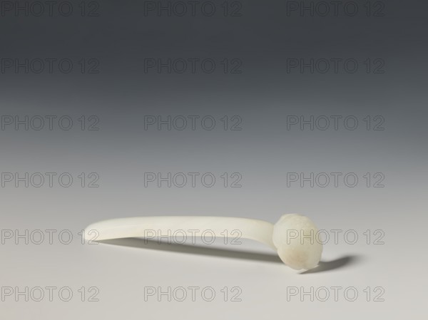 Hairpin, creator, Chinese; Qing dynasty 1644–1911, 18th–19th century; milky white jade, fully carved head with relief decoration; ruyi auspicious scepter iconography; function: hairpin/toiletry; dimensions: height 1.9 cm, width 2.7 cm, depth 10.4 cm., An off-white, smooth elongated object with a rounded decorative end rests on a flat surface, casting a soft shadow; the background transitions from dark gray at the top to light gray near the surface, and the colors visible are off-white, light gray, and dark gray.