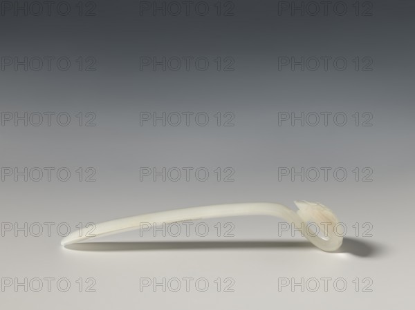 Hairpin, Chinese; Qing 1644–1911; 18th–19th century; milky white jade, fully carved head with relief decoration; ruyi auspicious scepter motif; toiletries; height 1.9 cm, width 2.7 cm, depth 10.4 cm., A single curved object rests on a flat surface, appearing smooth and translucent with an off-white to pale cream color; the background transitions from dark gray at the top to lighter gray toward the bottom, and the object casts a soft shadow beneath it with darker gray tones.