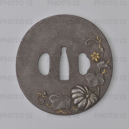 Crossguard tsuba, Masayoshi. Round tsuba maru gata with a rectangular edge kaku mimi, decorated on both sides with an asymmetrically composed high relief—carved takabori and inlaid with copper and gold takazôgan—depicting a plump pumpkin fruit with decoratively twisting stems, leaves and flowers. Details made with gold inlay using the nunome technique. Signed. 1st half of the 19th century Edo period, 1603–1868. Japan, Inaba historical province. Materials/subjects: metals, Japanese art; motifs include pumpkins, buffalo zodiac, plants. Tsuba; height 8.0 cm, width 8.35 cm, depth 0.45 cm., A round dark gray metal disk with three irregular central openings, decorated with a carved pumpkin and leaves near the lower right edge, a small flower and curling vine above the pumpkin, and thin winding vine accents; the carved elements include highlights in metallic silver and small accents in metallic gold, and the background surface is a textured matte gray.