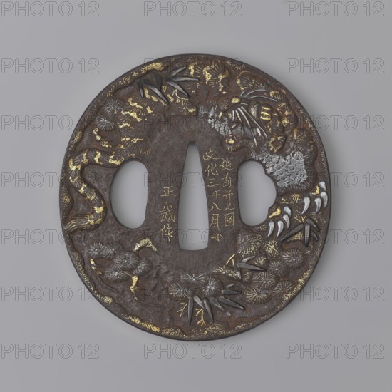 Crossguard tsuba, Masashige. Round tsuba maru gata with a slightly raised, irregularly outlined edge highlighted by a delicate gold nunome inlay. Decorated on the obverse with a tiger, bamboos and pine; on the reverse with a dragon among sea waves and lightning; details inlaid with gold and shakudo patinated copper. Signed. 1806 Edo period, Bunka 3, 8th month. Japan; Echizen. Tsuba; height 7.5 cm, width 7.8 cm, thickness 0.55 cm., A round metal object with a dark brown surface and areas of gold and silver embellishment, featuring an irregular central opening flanked by two rounded openings, with raised decorative motifs of leaves, flowers, and curved organic forms arranged around the perimeter, a few clusters of pointed leaf shapes, several textured floral rosettes, and a group of curved claw-like shapes; the background is a smooth pale gray.