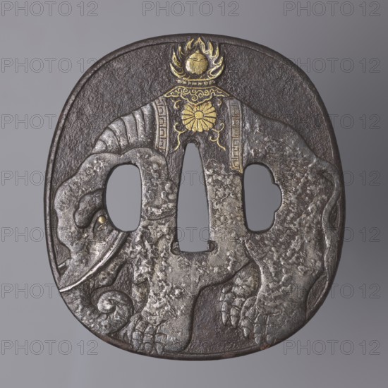 Crossguard tsuba, Tsuchiya Yasuchika 1670–1744. Nara school. Japanese, Edo period 1603–1868, 18th/19th century. Iron tsuba in the nadegaku gata rectangle with rounded sides shape with a slightly raised rounded edge uchi kaeshi. Obverse: low-relief image of an elephant covering almost the entire plate; on the animal’s back a saddle cloth decorated with a rosette and tendril border with a meander, and a Buddhist flaming jewel Cintamani symbolizing liberation through the Buddha. Reverse: large rectangular inscription in kanji — a fragment of the Lotus Sutra; lengthy inscription relating to the arrival of the elephant in Japan. Height 8.7 cm, width 7.9 cm, thickness 0.4 cm., A single carved oval metal object with a textured dark brown surface and areas of worn silver-gray on raised relief showing a stylized elephant motif; the elephant forms the central negative spaces and has a curved trunk, tusk, and textured legs with carved toes. There are a few decorative gold-colored accents at the t...