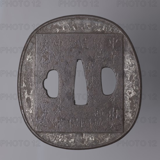 Crossguard tsuba, Tsuchiya Yasuchika 1670–1744, Nara school. Tsuba in the shape of a rectangle with rounded sides nadegaku gata, with a slightly distinct and rounded edge uchi kaeshi. On the obverse, low relief image of an elephant covering almost the entire surface; on the animal's back a saddle cloth decorated with a rosette and tendril border with a meander, and a Buddhist flaming jewel Cintamani. On the reverse a large rectangle with an inscription in kanji — a fragment of the Lotus Sutra; the backside bears a lengthy inscription relating to the arrival of the elephant in Japan. 18th/19th century Edo period, 1603–1868, Japan. Tsuba; height 8.7 cm, width 7.9 cm, depth 0.4 cm., A close-up view of a square-edged, rounded metal object with a central vertical opening flanked by two irregularly shaped side openings, showing a textured, pitted surface. The object displays a dark brown to almost black patina with areas of lighter gray and silvery patches where the surface appears worn. The...
