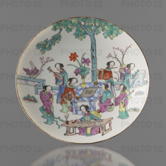 Platter, Chinese; Qing dynasty, Tongzhi period 1862–1874. Porcelain platter with white transparent glaze, decorated with overglaze enamels and iron red, gilded edge. Painted figural scenes of women, scholars, musical instruments; motif related to the game go. Vessel porcelain pot form, height 8.5 cm, diameter 21 cm, dated 1862–1874., A round porcelain plate with a painted scene dominated by a tree with green and blue leaves and a blue trunk, set against a white background and a thin brown rim; a group of figures wearing robes in colors such as pink, purple, green, blue, yellow, red, and orange are arranged around a central low table and another small blue-and-white table, with some figures holding objects and one seated at a wooden table in front; additional elements include a vase with a large red flower and purple blossoms, branches with small pink blossoms, a pale blue rock, small patches of green vegetation, and decorative architectural forms in light blue and teal; the composition...