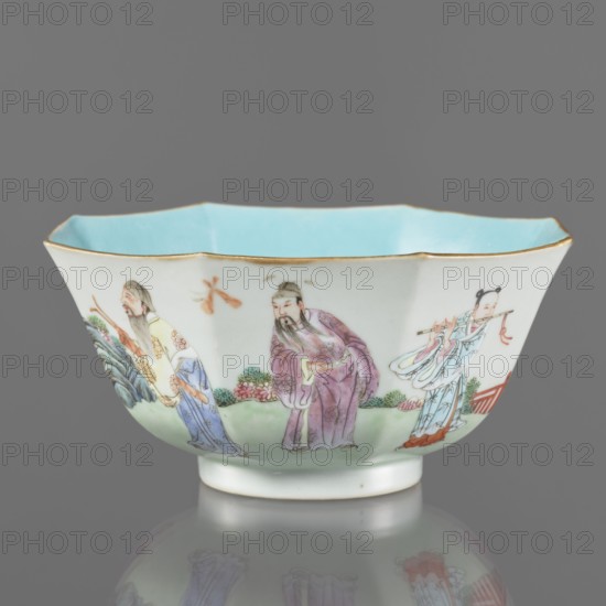 Bowl. Spherical bowl on a ring foot. Porcelain body with turquoise and transparent white glaze. Decoration painted with enamel paints and iron red depicting the Eight Immortals iconography. Colored porcelain, Qing dynasty, Jiaqing period 1796–1820, 18th/19th century China. Height 8.1 cm; diameter 17.6 cm; weight 0.4 kg.,  noted., A shallow porcelain bowl with a scalloped rim and a pale blue interior, edged in gold, sits against a neutral gray background; the exterior shows a painted scene of a group of figures wearing flowing robes in colors including purple, light blue, pale yellow, and white, with details in green, pink, orange, and red, set above a green ground with foliage and floral elements, and the bowl casts a faint reflection on the surface beneath it.