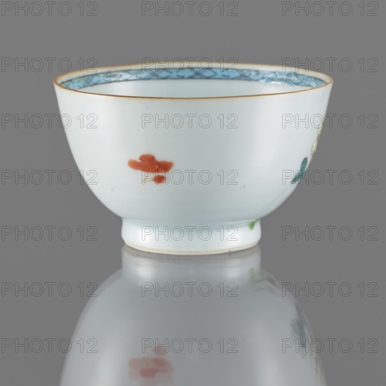 Bowl, Porcelain bowl with spherical form; white, transparent glaze with a bluish tint. Decoration painted with overglaze enamel paints depicting flowers. Qing dynasty, 19th century Qing, 1644–1911. Chinese colored porcelain. Vessel; height 5.5 cm, diameter 8.8 cm., A smooth white porcelain bowl with a slightly flared rim and a short foot, decorated on its exterior with small painted floral motifs in red and green and a painted blue band visible along the inner rim, all shown against a neutral gray background with the bowl’s reflection visible on the glossy surface below; visible colors include white, red, green, blue, gray, and a thin line of warm brown along the rim.