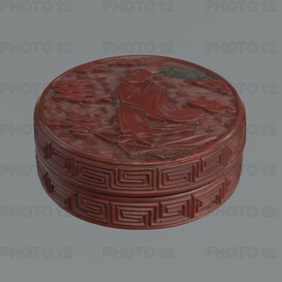 Box with lid; maker, Chinese, Qing dynasty 1644–1911. Red lacquer with carved pattern of reeds, meander leiwen, clouds and Buddhist motifs. 19th century. Vessel with lid: height 2.3 cm, diameter 8.8 cm a; height 3.5 cm, diameter 8.9 cm, base: height 1.8 cm, diameter 8.8 cm b; box: height 3.1 cm., A round carved container with a deep red color sits against a gray background, showing a carved figure reclining on the lid surrounded by carved cloud-like shapes; the sides feature repeating geometric raised patterns in the same red, with areas of darker red and small spots of darker wear.