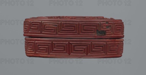Box with lid;, Chinese, Qing dynasty 1644–1911, 19th century. Red lacquer with carved pattern of reeds, meander leiwen, and clouds; Buddhist subject. Vessel with lid: height 2.3 cm, diameter 8.8 cm a; height 3.5 cm, diameter 8.9 cm, base: height 1.8 cm, diameter 8.8 cm b; box: height 3.1 cm. ., A horizontal, rectangular object with carved geometric patterns on its visible faces, showing a repeating stepped motif across the top and bottom sections; the carved surface appears worn in places with a rougher, darker patch on one area; the piece is primarily a deep red color with subtle variations of darker and lighter red, and there is a neutral gray background.