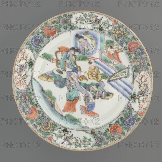 Plate. Porcelain fragment with white glaze; decoration painted with overglaze enamel paints and iron red. Colored porcelain with plant motifs and figural scenes. Qing dynasty 1644–1911, 18th century, China. Height 2.4 cm; diameter 20.4 cm; weight 0.35 kg. Chinese ceramics., A round porcelain plate with a pale gray background shows a central painted scene of a group of figures in traditional clothing amid stylized rocks and architectural elements; the figures wear garments in colors including green, blue, purple, orange, yellow, and red, with one figure seated on a carved chair and others standing or kneeling, some holding handheld objects. Surrounding the central scene is an ornate border of floral and bird motifs rendered in green, purple, blue, orange, yellow, and white, with several cloud-shaped cartouches containing small floral sprigs and birds, and a thin gilded rim around the plate edge.