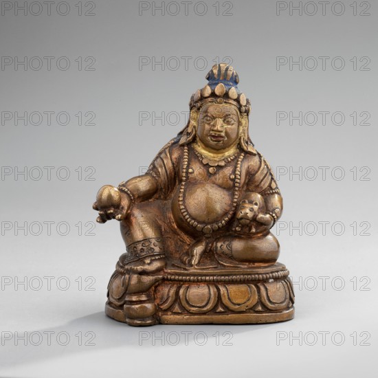 Jambhala, Himalayan culture, Tibetan Buddhist/Himalayan art, dharmapala iconography, lotus throne iconography, cast copper with gilded face later; polychrome lips, eyes, and hair, mid-19th century, Mongolia, sculpture/figurine, height 6.7 cm, width 5.3 cm, depth 4.0 cm, A small metallic figurine sits on a carved rounded base, showing a seated humanlike figure with a rounded belly, ornate jewelry including a beaded necklace, and a crownlike headdress; the figure holds a rounded object in one hand and a small animallike head in the other, and wears decorated arm and leg bands. The colors visible are bronze, gold, blue, and touches of darker brown, set against a neutral light gray background.
