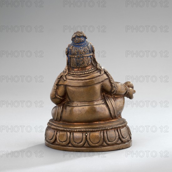 Jambhala, Himalayan culture, Tibetan Buddhist art, Himalayan art, dharmapala iconography, lotus throne iconography, cast copper, gilded face later; polychrome lips, eyes, and hair, mid-19th century, Mongolia, sculpture, figurine, height 6.7 cm, width 5.3 cm, depth 4.0 cm, A small sculpted figure shown from the rear seated on a rounded base, rendered in metallic brown with traces of blue on the top of the head; the figure wears layered garments and a detailed headdress with textured strands and ornamental bands, and has rounded shoulders, arms bent at the sides, and a rounded back and folded legs; the base is decorated with repeating petal-like motifs and beaded edging; the background is a smooth neutral gray.