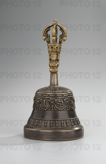bell; Tibetan Buddhist art; Himalayan art; Mongolian art; Himalayan, Mongolian cultures; vajra; musical instrument; percussion instrument; idiophone; ritual/ceremonial object used in religious rites; late 18th century ; Mongolia ; height 15.7 cm; diameter 8.2 cm; provenance: purchase., A metal handbell with a decorative handle and a flared bell body sits against a neutral background; the handle is ornate and gold-colored with sculpted curved elements and carved details, while the bell body is darker bronze or brown with embossed decorative bands and patterned relief around its mid and lower sections, and the top of the bell has a carved floral-like design; the background is a smooth grey gradient.