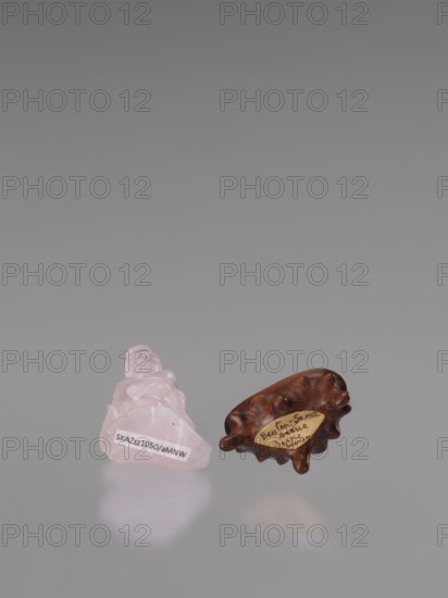 Guanyin on a base; carved rose quartz figurine, full sculpture with engraving; goddess from Chinese Buddhism; Chinese, Qing dynasty 1644–1911; 19th century; height 6 cm;, A small pink translucent carved stone figure sits next to a small brown wooden object with a smooth, rounded, irregular shape; the background is a smooth gradient of gray.