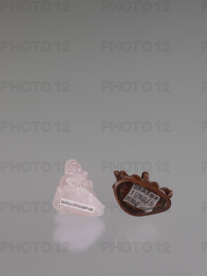Guanyin on a base, figurine carved in rose quartz, full sculpture with engraving, 19th century China Qing, 1644–1911, Chinese Buddhism goddess, sculpture, height 6 cm, A small translucent pink carved stone figure sits next to a small brown carved wooden object with an irregular oval hollow; both objects rest on a reflective gray surface and cast soft reflections, with a smooth light gray background.