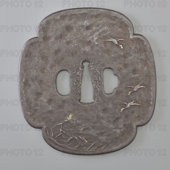 Crossguard tsuba, Kaneie craftsman, geese, sword crossguards, mokkô. Tsuba for a tachi sword. Quatrefoil shape mokkô gata with a slightly raised edge of the uchi kaeshi or ryôhitsu ana type. Decorated on the obverse with wild geese flying over a water's edge overgrown with reeds; on the reverse, sails of three boats at the top and fishing nets drying on the shore below. Gold-inlaid details. Signed. Early 19th century Edo period, 1603–1868. Fushimi, Yamashiro, Japan. Tsuba; height 10.9 cm, width 10.2 cm, depth 0.45 cm., A roughly square metal object with rounded lobed edges in dark gray and brown tones, showing a textured, weathered surface; three rounded cutouts near the center and a narrow central cutout create openings; a few stylized birds in lighter gray with small touches of yellow are depicted flying on the right side and upper area; near the lower edge a group of carved rock-like shapes in gray include small yellow highlights and a short sprig-like element; subtle variations in ...