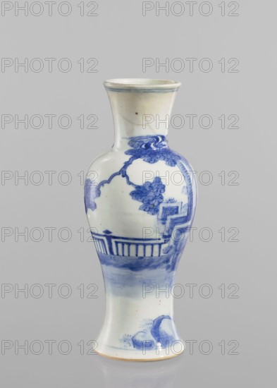Vase, figurative scenes, ceramics, Chinese art, Chinese culture, blue-and-white porcelain, terraces architectural motif, origin provenance: China, Qing 1644–1911, porcelain vase. Transparent blue-gray glaze; underglaze cobalt painted decoration. 19th/20th century. Vessel, height 24.3 cm, diameter 9 cm., A ceramic vase with a narrow neck, flared rim, rounded shoulder and slightly flared foot, painted in shades of blue and white; the surface shows a blue painted landscape motif with a group of tree-like forms and foliage, an architectural railing or fence, stepped elements, and stylized rock forms near the base; the background is white with areas of light blue wash, and the rim and foot edges show pale beige tones.