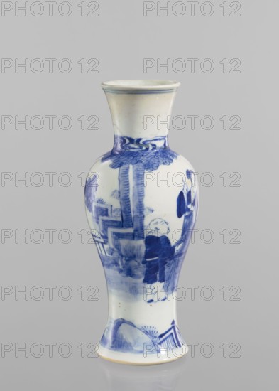 Vase, figurative scenes, ceramics, Chinese art, Chinese culture, blue-and-white porcelain, terraces architectural motif, provenance unknown, Qing dynasty 1644–1911, porcelain vase. Transparent blue-gray glaze; underglaze cobalt-painted decoration. 19th/20th century, China. Vessel; height 24.3 cm, diameter 9 cm., A tall ceramic vase with a flared rim and narrow foot, predominantly white with blue painted decoration, showing a scene with several human figures near stylized trees and architectural elements; the upper neck area has a band of blue foliage, the main body features a standing figure in dark blue clothing facing another figure among vertical tree trunks and stepped structures, and the lower section includes landscape motifs with rocks and a fence, all set against a plain light gray background.