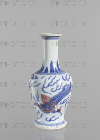 Vase, blue and white porcelain, Chinese, Qing 1644–1911, 19th century. Vessel decorated with dragons and pearls. Height 19.6 cm; diameter 9.3 cm., A ceramic vase with a narrow neck and flared rim standing on a rounded foot, decorated with hand-painted designs in blue and red on a white background; the neck shows a band of blue pattern near the rim and vertical blue leaf-like motifs at its base, the bulbous body features flowing blue cloud-like motifs and a stylized creature with red fins and blue body wrapping around the surface, and a patterned blue band encircles the foot.
