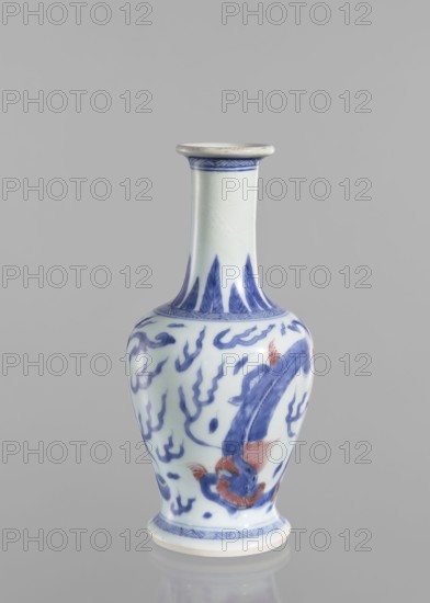 Vase, blue and white porcelain, Chinese art, Qing style Qing dynasty, 1644–1911, 19th century China; decorated with pearls and dragons iconography; vessel, height 19.6 cm, diameter 9.3 cm., A tall, narrow-necked porcelain vase with a flared rim and a rounded body sits against a plain gray background; the vase is primarily white with blue painted designs and touches of reddish-orange on the fish-like creature depicted on its body, featuring flowing blue wave and flame motifs around the form, a banded blue decorative border near the base and rim, and a glossy finish that reflects soft light.