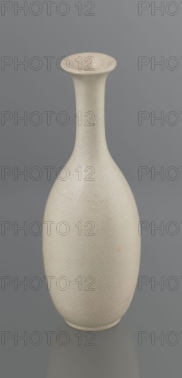 Vase on saucer. Vase made of stoneware or thick porcelain?, ovoid with a long cylindrical neck flaring at the spout. Light cream white matte glaze covered with fine cracklework. 19th century, Japan, Edo 1603–1868. Ceramics; bottles. Height 24.1 cm, diameter 8.6 cm, weight 0.65 kg., A tall, slender vase with a narrow neck that flares at the rim sits against a smooth gray background; the vase surface is an off-white or cream color with a fine network of subtle crackle lines and slight variations in shading, and there are small darker specks and a faint warm-toned spot on the body.