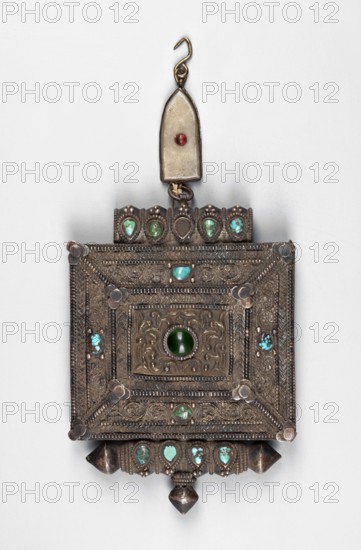 Ga'u box, gift, Himalayan Tibetan Buddhist amulet/ceremonial container, 19th/20th century, Tibet; materials: jewelry/amulet; height 19 cm, width 8.5 cm, depth 2.3 cm., A rectangular metallic pendant with ornate engraved patterns and raised borders, featuring decorative round and teardrop cabochon stones in shades of green and turquoise set into the metal; a central round green stone is surrounded by embossed floral-like motifs, with several small turquoise-green stones arranged along the top and bottom edges and at corners; the metal shows a patinated silver-gray and bronze tone, with darker shadowed areas and small highlights; above the main pendant a small elongated metal plate with a single small round red bead is attached to a hooked suspender in a brass-like color.