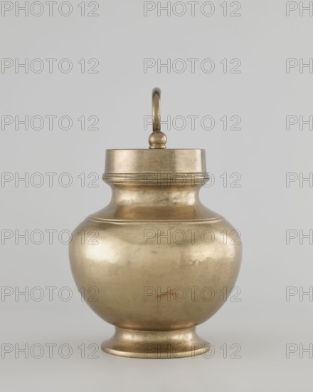 Teapot, 19th/20th century, Burma Myanmar, art of Southeast Asia, vessel/container, height 22.0 cm, diameter 14.3 cm, A rounded metal vessel with a lid and looped handle sits centered against a plain light gray background; the vessel has a bulbous body tapering to a short pedestal base and a neck that widens into a flat-topped lid, all showing a metallic golden-brass color with subtle darker patina and small surface marks, while the handle and decorative banding share the same golden-brass hue.