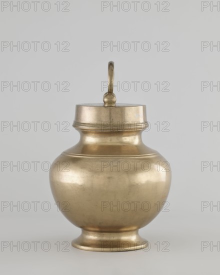 Teapot, gift, 19th/20th century, Burma Myanmar, Southeast Asian art, vessel/container, height 22.0 cm, diameter 14.3 cm, A metallic vessel with a rounded body and a narrow neck topped by a lid with a looped handle sits against a plain light gray background; the vessel has a muted gold or brass color with subtle reflective highlights and areas of slightly darker patina, a flared footed base, and a simple raised band detail around the shoulder and lid.