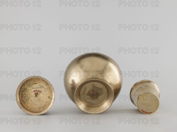 Teapot, gift, art of Southeast Asia, Southeast Asia culture, 19th/20th century, Burma Myanmar, vessel, container, height 22.0 cm, diameter 14.3 cm, A group of three metallic vessels placed on a flat surface against a pale gray background, each shown from a low angle revealing their undersides; the vessel at center is a large rounded bowl with a reflective brass-like surface showing worn areas and subtle surface marks, the vessel at left is a shallower dish with a textured interior and a mottled patina of darker spots on its brass-colored surface, and the vessel at right is a narrower cup-shaped piece with a similar brass tone and smoother finish; overall the visible colors are brass-gold, pale gray, and small areas of darker brownish discoloration.