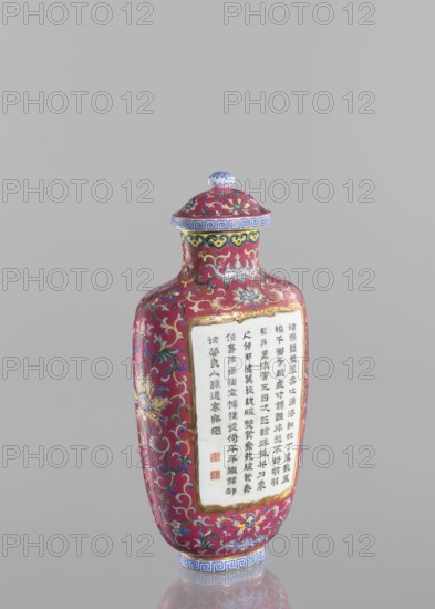 Vase with lid. Chinese. Qing dynasty, Qianlong period 1736–1795. Colored porcelain with lid; flattened vase form. Decoration: lotus tendril ornament, inscriptions of poems/poetry. Height 22.7 cm; width 10.7 cm; weight 0.65 kg., The image shows a decorative bottle with a lid set against a plain light gray background. The bottle is primarily a deep red color with ornate scrolling floral patterns in colors including blue, yellow, green, white, and gold. The lid has a rounded knob with blue and white detailing and a band of blue geometric pattern around its rim. A rectangular panel on the front of the bottle is white and bordered in gold, surrounded by the red and multicolored floral design that continues over the bottle's surface. The base of the bottle has a blue and white geometric band and the overall shape is elongated with a narrow neck and rounded shoulders.