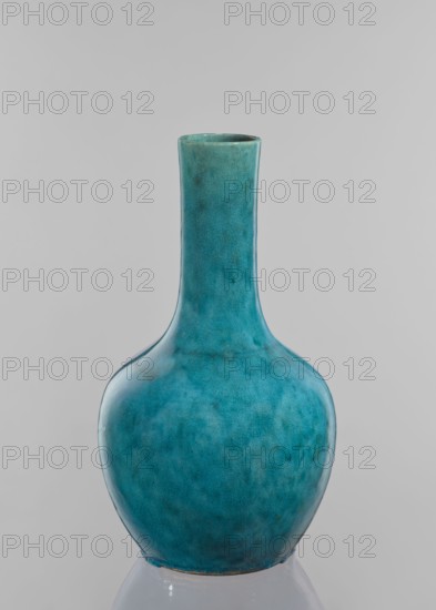 Vase-bottle; maker, ; Chinese; cracklework decoration; uniform blue-green glaze with fine cracklework; 19th century; China; vessel; height 33 cm, diameter 18 cm., A ceramic vase with a rounded body and a long narrow neck sits against a plain light gray background, showing a smooth glossy surface with a crackled texture; the vase displays a mix of turquoise, teal, and blue-green hues with subtle darker teal and blue mottling and faint areas of greenish tones, and the rim and base show slightly different, more muted greenish-blue shading.