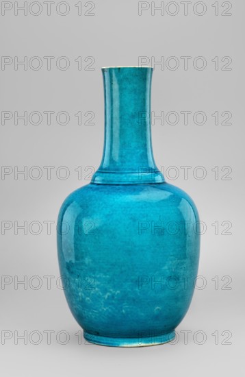 Vase, ovoid vase with a long neck, slightly widened in the lower part and at the rim, separated from the body by a ring; on a low foot; monochromatic blue-green glaze with very fine cracklework; Chinese, Qing dynasty, Kangxi period 1662–1722; porcelain/ceramic vessel; height 33.6 cm; dated 1662–1722., A single tall vase with a rounded body and a long narrow neck stands against a plain light gray background; the vase is a glossy turquoise blue with subtle variations in tone and texture, showing areas of lighter and darker blue and small mottled patches, and the rim and base show thin traces of a pale off-white color.