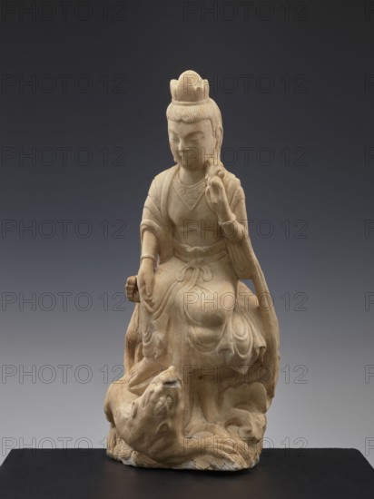 Guanyin with qilin, Chinese, Qing dynasty 1644–1911, 19th century, Chinese Buddhism iconography depicting a goddess with a unicorn qilin, sculpture/figurine, height 47.5 cm, A pale beige stone sculpture of a seated figure wearing a crown-like headdress and flowing robes sits on a dark base against a gradient gray background, the figure's facial features are calm with closed eyes, one hand raised near the shoulder and the other resting on the knee, the drapery of the robes shows carved folds and a tied sash at the waist, beneath the seated figure a carved animal-like form with a rounded head and open mouth appears integrated into the base, the visible colors are beige, dark gray, and lighter gray.