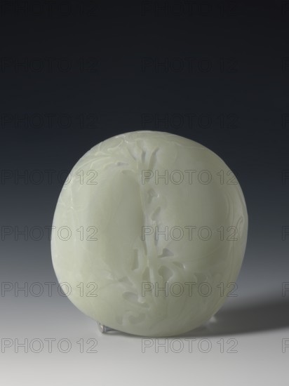 Plaque-lid, maker, 19th century Qing dynasty 1644–1911, China. Bas-relief carved jade plaque-lid with engraving, depicting bats and plant motifs; three double recesses on the bottom. Height 14.2 cm, width 15.4 cm., A smooth, round object with a pale green, almost white surface sits against a dark gray to black gradient background, showing subtle carved relief patterns and gentle glossy highlights; the object rests on a small clear support casting a faint shadow onto a light gray surface below.