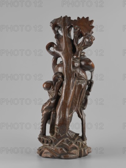 Mythical figure, unknown sculptor; Chinese and Japanese art; pine trees; mythology; beasts fantasy; unicorns iconography; fantasy animals; Qing dynasty 1644–1911; 2nd half of the 19th century; possibly China or Japan as place of origin; sculpture, figurine; height 47.0 cm., A carved wooden sculpture with a rich dark brown finish stands on a carved base that resembles layered, undulating forms. A central tall, irregular vertical element with a textured surface rises from the base and is flanked by organic, curving forms that twist and loop around it. Several bulbous, rounded shapes and elongated, sinuous limbs intertwine, creating a complex, openwork composition with smooth and carved surfaces. The overall surface shows variations in brown tones with polished highlights and darker recesses, and the background is a uniform light gray.