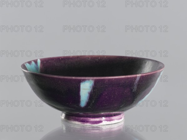 Bowl, gift; vessel, ceramic; Qing dynasty 1644–1911, 18th–19th century, China; purple glaze with celadon spots; manganese and copper, glaze; height 6.7 cm, diameter 18.1 cm., A shallow ceramic bowl with a rounded rim and a small foot, primarily finished in deep purple with several vertical patches of turquoise-blue on the exterior and interior, the glaze showing subtle variations in tone and a slightly glossy surface, set against a plain light gray background.