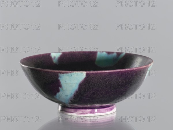 Bowl, ceramic vessel, Qing dynasty 1644–1911, 18th–19th century, China. Purple glaze with celadon spots; manganese and copper glaze. Height 6.7 cm; diameter 18.1 cm., A shallow ceramic bowl with a rounded rim and a short foot, showing a glossy surface in deep purple and teal with patches of lighter blue-green; the interior and exterior share the same color pattern, and the foot has visible bands of purple and white; the background is a smooth light gray.