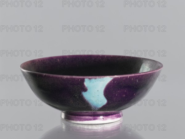 Bowl, gift, vessel; ceramics, Qing dynasty 1644–1911, 18th–19th century, China; purple glaze with celadon spots; manganese and copper, glaze; decorative vessel; height 6.7 cm, diameter 18.1 cm., A shallow ceramic bowl with a rounded rim and a short foot, glazed predominantly in deep purple with areas of blackish shading and a distinct irregular patch of light blue on one side, the interior appearing dark with purple along the rim, the foot showing a band of purple over a pale base, all set against a neutral light gray background.