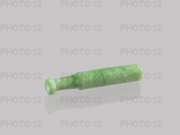 Cigarillo, creator unknown, Chinese, Qing dynasty 1644–1911, 19th century. Cast glass, green and white. Smoking tobacco pipe, height 7.9 cm, diameter 1.35 cm., A single cylindrical object lies on a pale gray background, showing a mottled green and white marbled surface. The object has a flared rounded end and a slightly tapered middle before returning to a straight cylindrical section, with a faint shadow and reflection beneath it. The overall visible colors are shades of green, white, and pale gray.