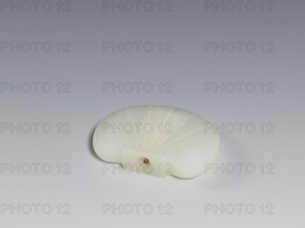 Snuffbox with spoon, Chinese, Qing dynasty 1644–1911, pale green jade with relief decoration, decorative vessel, 18th–19th century, China; height 4.85 cm, width 3.7 cm, thickness 1.05 cm., A smooth, pale off-white object shaped like a flattened shell with radiating carved grooves resting on a smooth surface, casting a soft shadow; the background transitions from light gray at the bottom to a darker gray toward the top, and there is a small darker beige spot in a recessed area on the object.