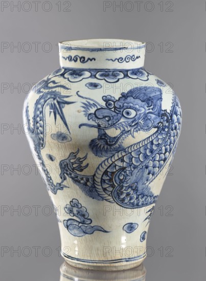 Vase, Korean, Joseon 1392–1897, 18th century. Ovoid vessel with a long neck, maebyeong mei-ping type. Decoration: two dragons among clouds. Height 46.0 cm; width 32.0 cm; weight 8.0 kg., A ceramic vase with a rounded shoulder and narrow base shown against a neutral background, decorated in blue on a pale off-white ground with a painted serpentine dragon motif wrapping around the body, stylized cloud and wave forms, and floral or abstract scroll borders near the neck and base; the glaze shows crackling and a few glaze imperfections, and the dominant colors visible are blue, off-white, and subtle beige tones.